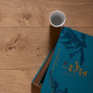 Wooden floor with a blue book and white cup on top