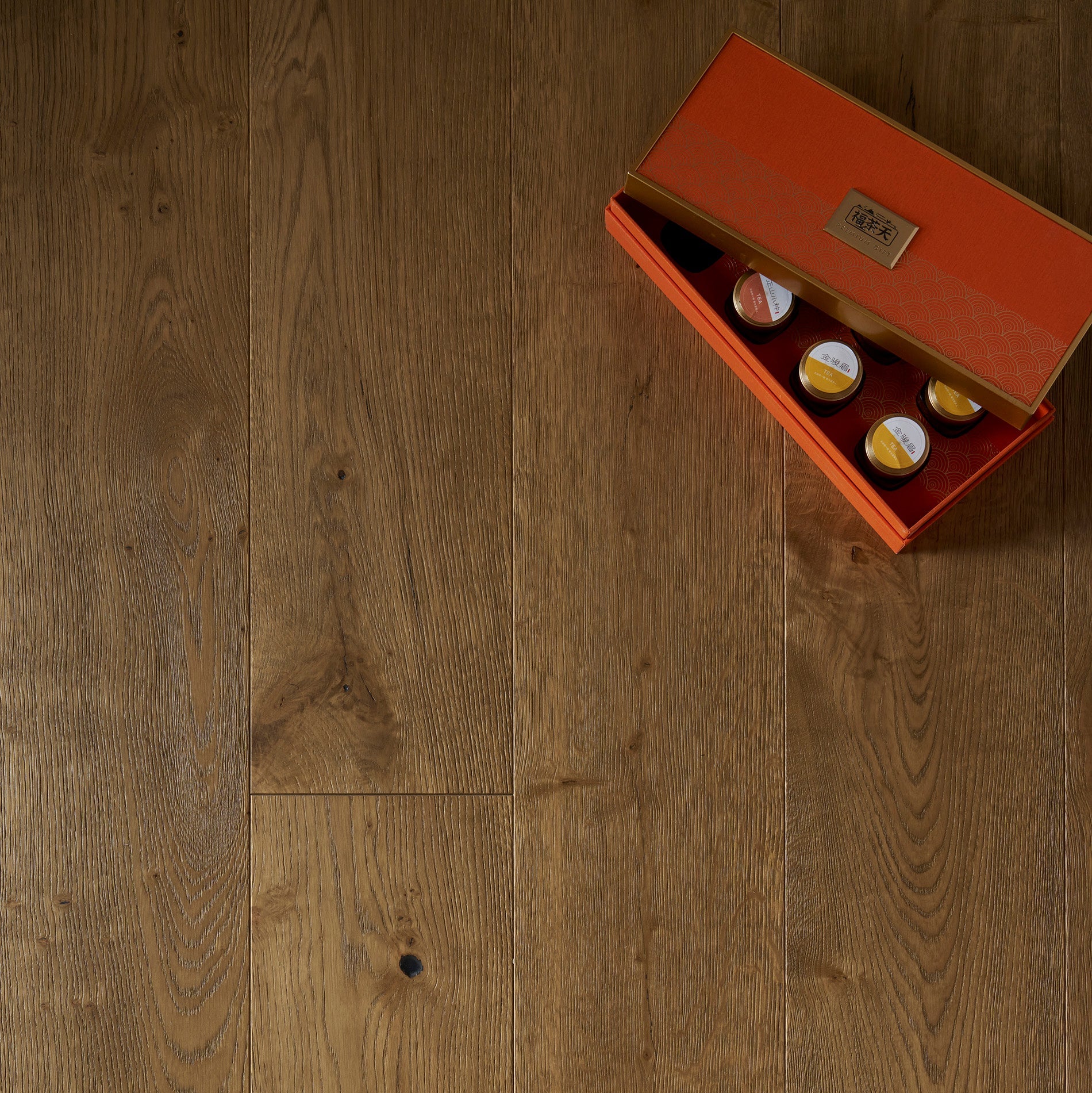 Wooden floor with a small orange box containing three bottles on top