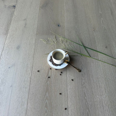 Cup and saucer with scattered coffee beans on a wooden floor